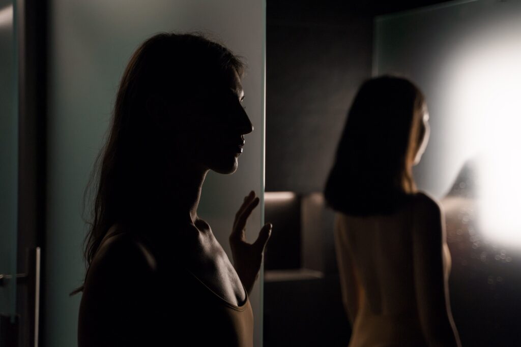 Mujer frente al espejo por la mañana sin reconocerse por culpa a una baja autoestima tras una ruptura.