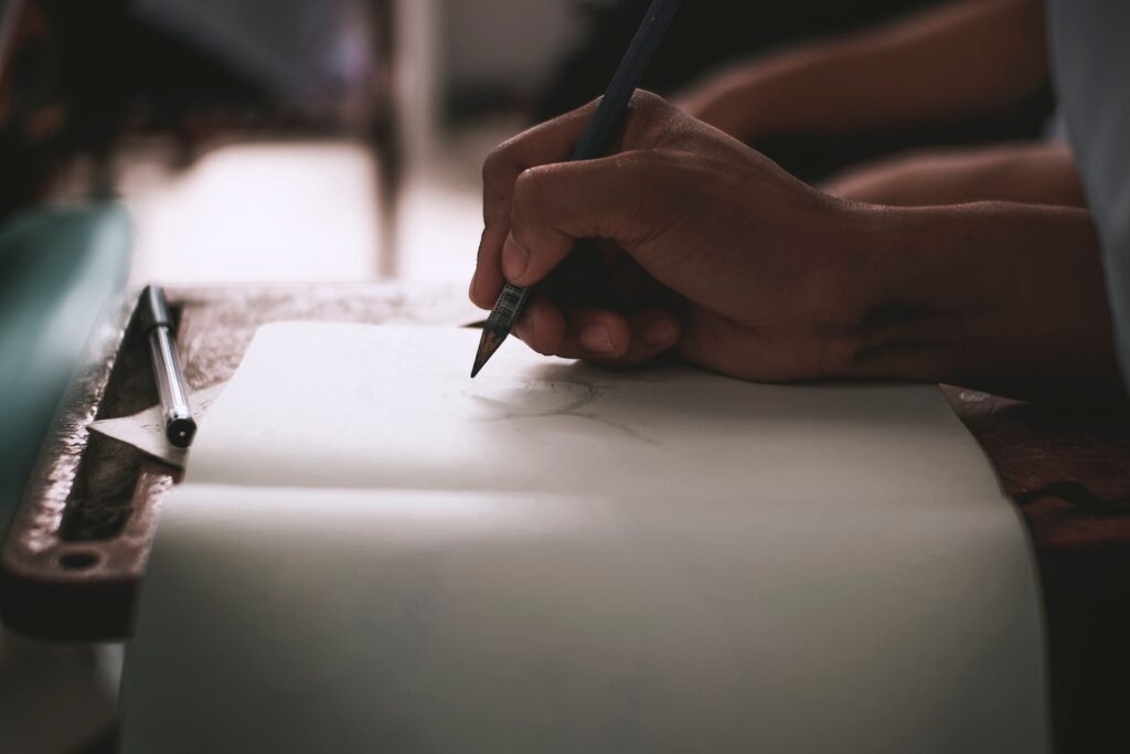 Manos escribiendo a mano en una libreta. Directo, funcional, refuerza la instrucción de "papel y lápiz, no el teléfono