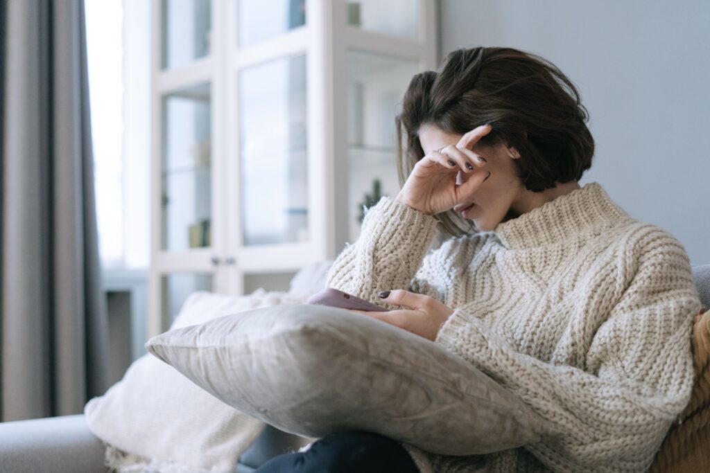 mujer mirando el teléfono con tensión, no dramatizado, solo atenta esperando algo.